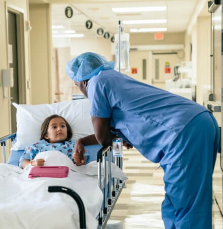 Doctor haelt die Hand eines Kindes, dass im Krankenbett liegt