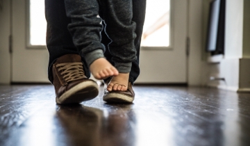 Mały chłopiec (2 lata) chodzący na stopach ojca, zbliżenie